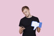 Foto: Young man with cell phone holding fake dislike button against pink background Young man with cell phone holding fake dislike button against pink background