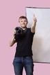Photo: Happy photographer holding camera with thumbs up gesture over pink background Happy photographer holding camera with thumbs up gesture over pink background