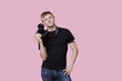 Photo: Portrait of a happy young male photographer holding camera over pink background Portrait of a happy young male photographer holding camera over pink background