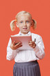 Photo: Portrait of a happy young schoolgirl holding tablet PC over orange background Portrait of a happy young schoolgirl holding tablet PC over orange background