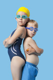 Photo: Profile shot of young boy and girl in swimwear standing back to back over blue background Profile shot of young boy and girl in swimwear standing back to back over blue background