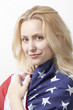 Photo: Portrait of beautiful young Caucasian woman wrapped in American flag against white background Portrait of beautiful young Caucasian woman wrapped in American flag against white background