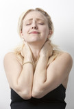 Photo: Young Caucasian woman suffering from neckache standing against white background Young Caucasian woman suffering from neckache standing against white background