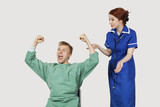 Photo : Young male patient with female nurse celebrating success against gray background Young male patient with female nurse celebrating success against gray background