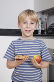 Photo: Portrait of cute little boy choosing between apple and chocolate chip cookie Portrait of cute little boy choosing between apple and chocolate chip cookie