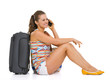 Happy tourist woman sitting near wheel bag and talking mobile