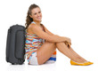 Smiling young tourist woman sitting near wheel bag