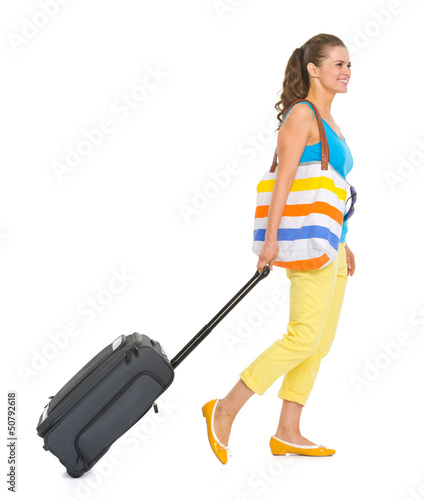 Photo: Young tourist woman with wheel bag going sideways Young tourist woman with wheel bag going sideways