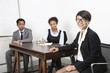 Photo: Portrait of Asian female with multiethnic colleagues in background at desk in office Portrait of Asian female with multiethnic colleagues in background at desk in office