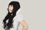 Photo: Side view of thoughtful young woman in doll costume looking away against gray background Side view of thoughtful young woman in doll costume looking away against gray background