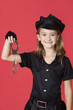 Photo: Portrait of young girl in police costume holding handcuffs against red background Portrait of young girl in police costume holding handcuffs against red background