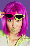Photo: Portrait of young funky woman in pink wig puckering lips over purple background Portrait of young funky woman in pink wig puckering lips over purple background