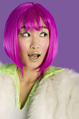 Photo: Surprised young funky woman in pink wig looking sideways over purple background Surprised young funky woman in pink wig looking sideways over purple background