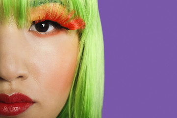 Photo: Cropped image of young woman wearing false eyelashes against purple background Cropped image of young woman wearing false eyelashes against purple background