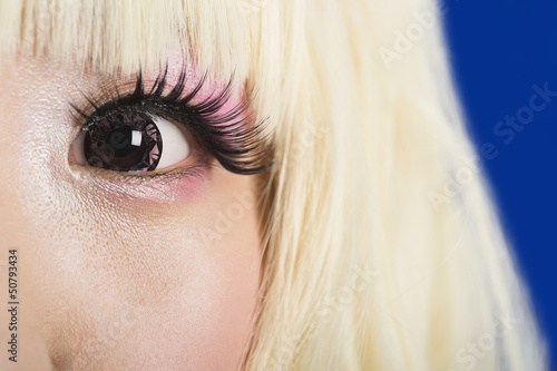Photo: Close-up portrait of cute young woman's face with blond hair against blue background Close-up portrait of cute young woman's face with blond hair against blue background
