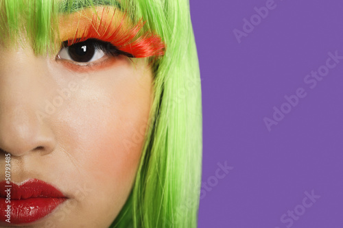 Photo: Cropped image of young woman wearing false eyelashes against purple background Cropped image of young woman wearing false eyelashes against purple background