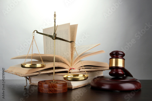 Photo: Golden scales of justice, gavel and books on grey background Golden scales of justice, gavel and books on grey background