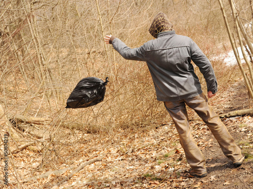 Photo: Neglectful man throwing out the garbage in the forest Neglectful man throwing out the garbage in the forest