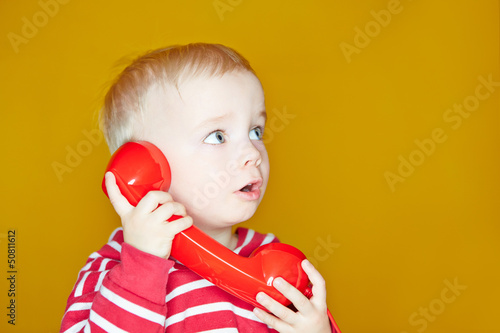 Photo: Kleines Kind hört am Telefon zu Kleines Kind hört am Telefon zu