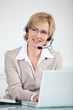 Woman using a telephone headset at a laptop computer