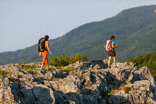 Photo: Two women is trekking in the Crimea mountains with backpacks Two women is trekking in the Crimea mountains with backpacks