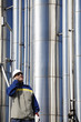 oil and gas pipelines with hardhat worker in foreground