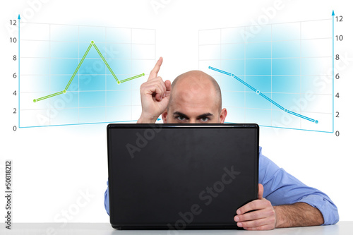 Photo: Businessman with a laptop and graphs Businessman with a laptop and graphs