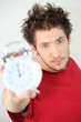 Young man holding an alarm clock