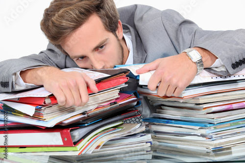 Photo: Man drowning in stacks of paperwork Man drowning in stacks of paperwork
