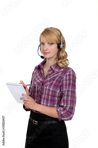 Photo: Woman in a headset writing in a notepad Woman in a headset writing in a notepad