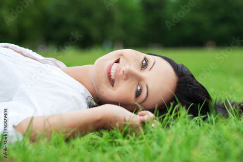 Photo: Smiling woman laying on grass Smiling woman laying on grass