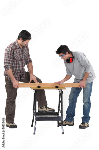Photo: Father and son securing plank of wood Father and son securing plank of wood