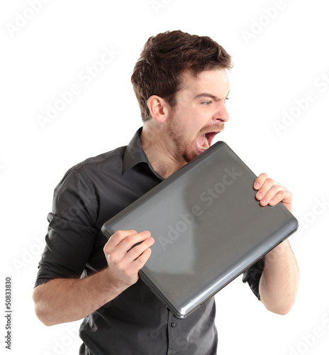 Photo: Angered office manager bites the laptop on a white background Angered office manager bites the laptop on a white background