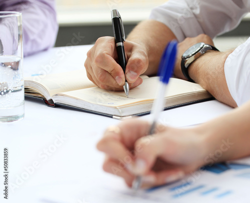 Photo: Hands writing on a paper Hands writing on a paper