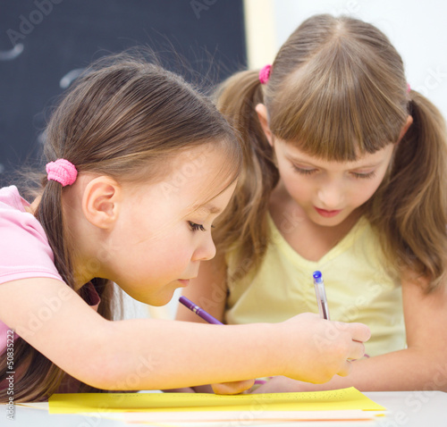 Photo: Little girls are writing using a pen Little girls are writing using a pen