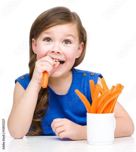 Photo: Cute little girl is eating carrot Cute little girl is eating carrot