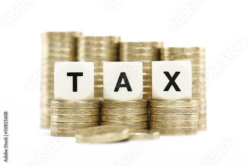 Photo: Tax in lettered dice on stacks of gold coins Tax in lettered dice on stacks of gold coins
