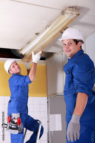 Photo: Electricians installing neon lights in the ceiling Electricians installing neon lights in the ceiling