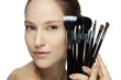 Portrait of the beautiful woman with make-up brushes.