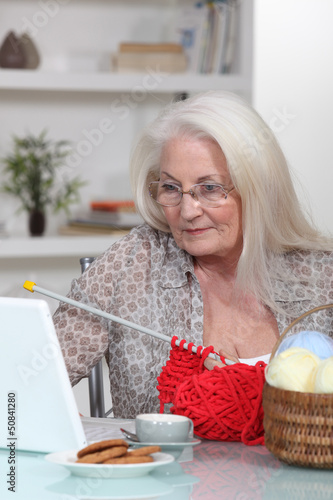 Photo: Elderly lady knitting by laptop Elderly lady knitting by laptop