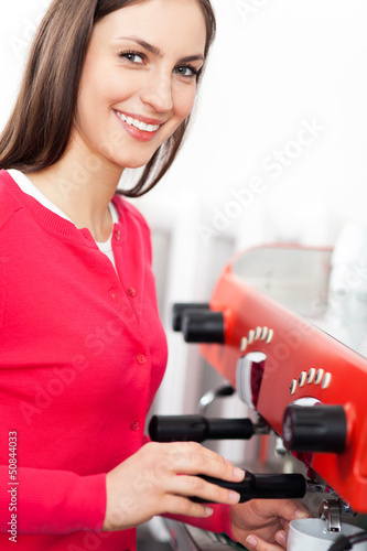 Photo: Female barista by coffee maker Female barista by coffee maker