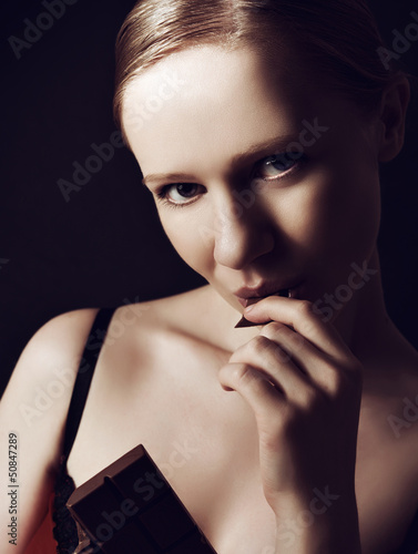 Photo: sexy beautiful young woman eating chocolate on a dark sexy beautiful young woman eating chocolate on a dark