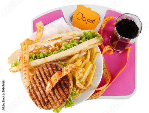 Photo: Hamburger, french fries on plate on scale isolated on white Hamburger, french fries on plate on scale isolated on white