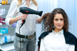 stylist drying woman hair in salon