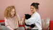 Two teenagers sitting on sofa cary on a cat - tracking shot