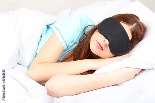 Photo: Beautiful young woman sleeping in bed with eye mask Beautiful young woman sleeping in bed with eye mask