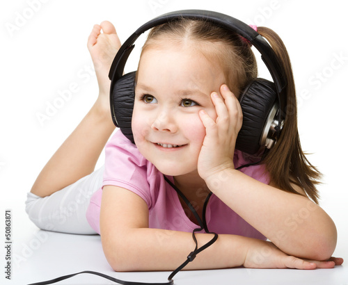 Photo: Cute little girl enjoying music using headphones Cute little girl enjoying music using headphones