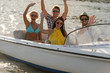 Waving young people sitting in motorboat