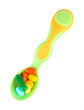 Plastic spoon with color pills, isolated on white