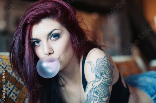 Photo: Sensual portrait of tattooed red head girl with chewing gum. Sensual portrait of tattooed red head girl with chewing gum.